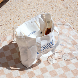 Tote with wine and wine glasses on picnic blanket