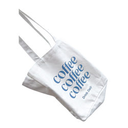 A white cotton tote bag with 'coffee coffee coffee' printed in blue text on the side, featuring two handles and a wine bottle pocket.