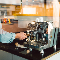 Person operating a rocket giotto espresso machine in a kitchen