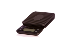 A black digital coffee scale with a backlit display, designed to fit an entire portafilter, indicating its use in coffee preparation.