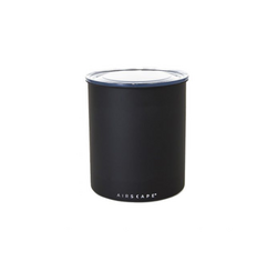 A black Airscape canister, a cylindrical kitchen appliance designed to keep coffee fresh by actively pushing air out.
